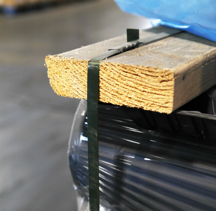 a dark green polyester strapping being used to palletize products using wood supports